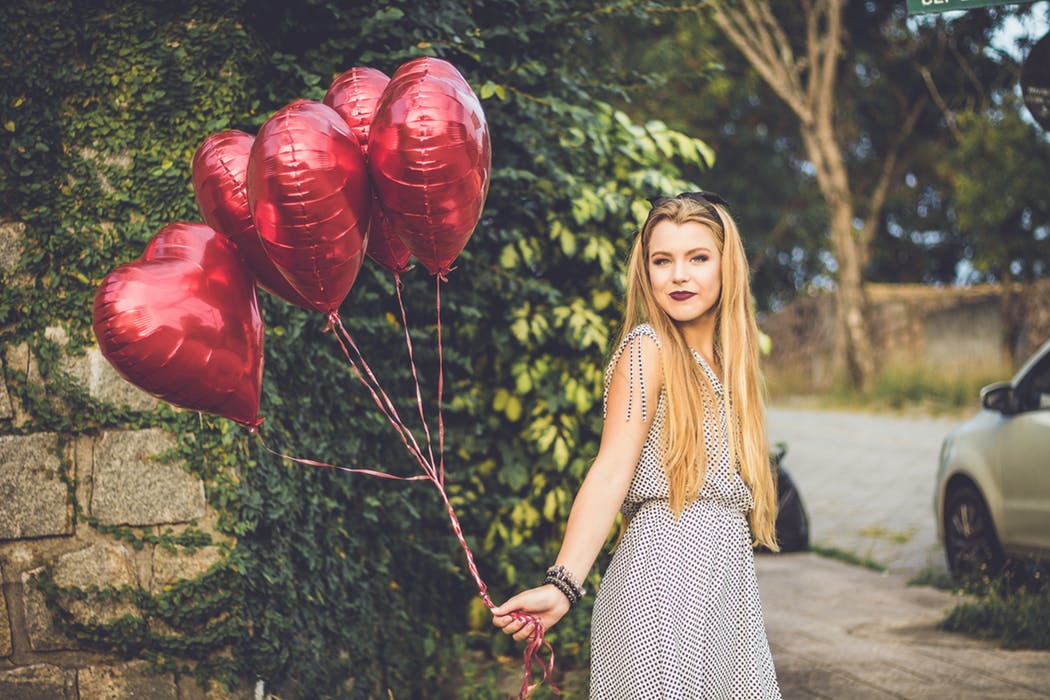 woman holding heart-shaped balloons